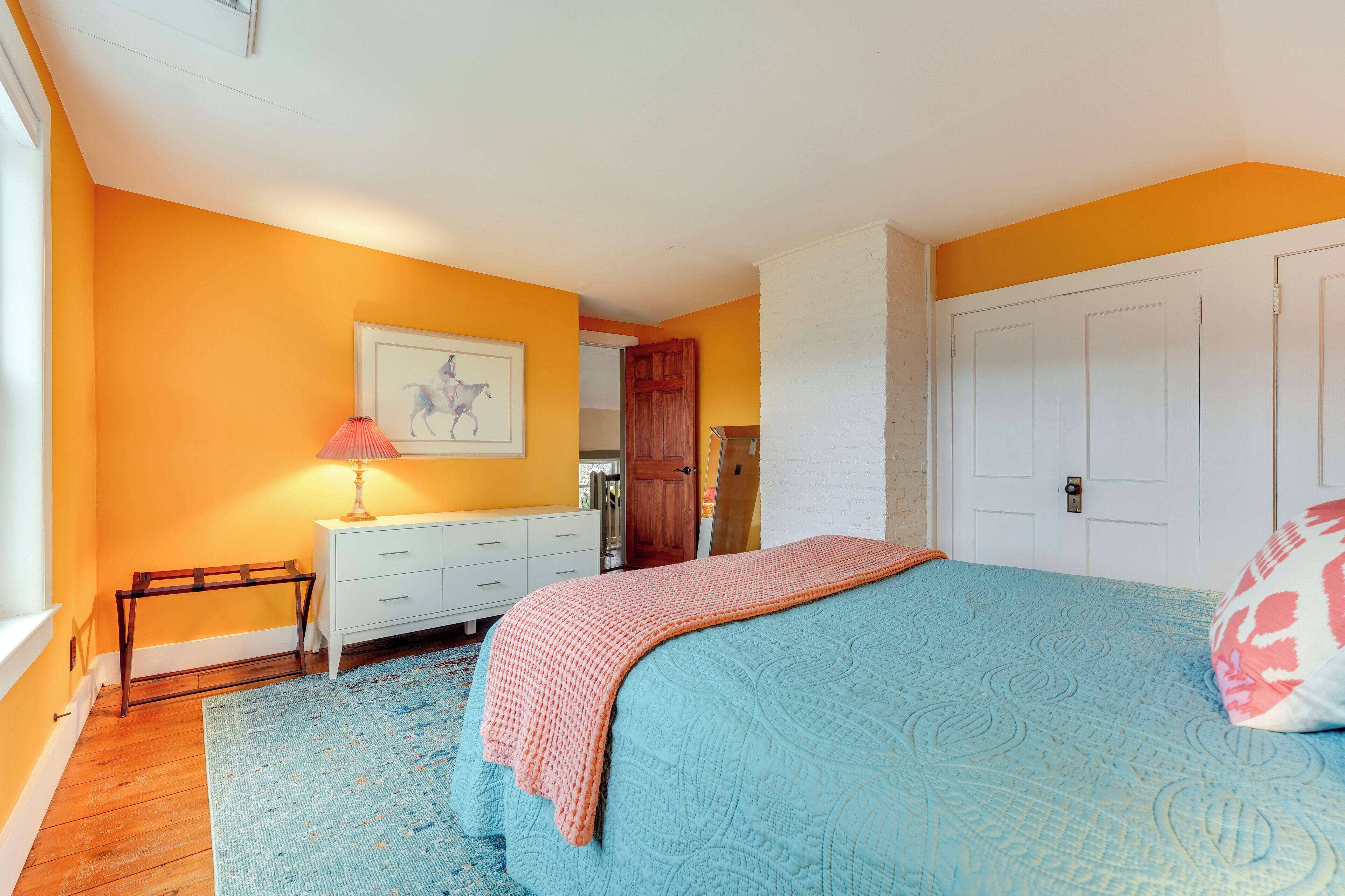 A bedroom with a bed, a nightstand, a lamp, and a door.