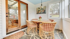 A cozy room with a wooden table and wicker chairs, a painting of fruit on the wall, and a large window. - Manchester Center Home w/ Green Mtn Views! (Manchester Center)