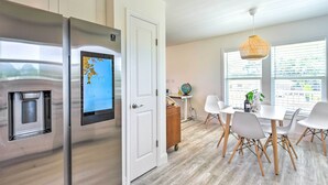 A modern kitchen with a stainless steel refrigerator, a white door, and a dining area with a white table and chairs. - Near Downtown + Ocean: Sarasota Getaway (Sarasota)