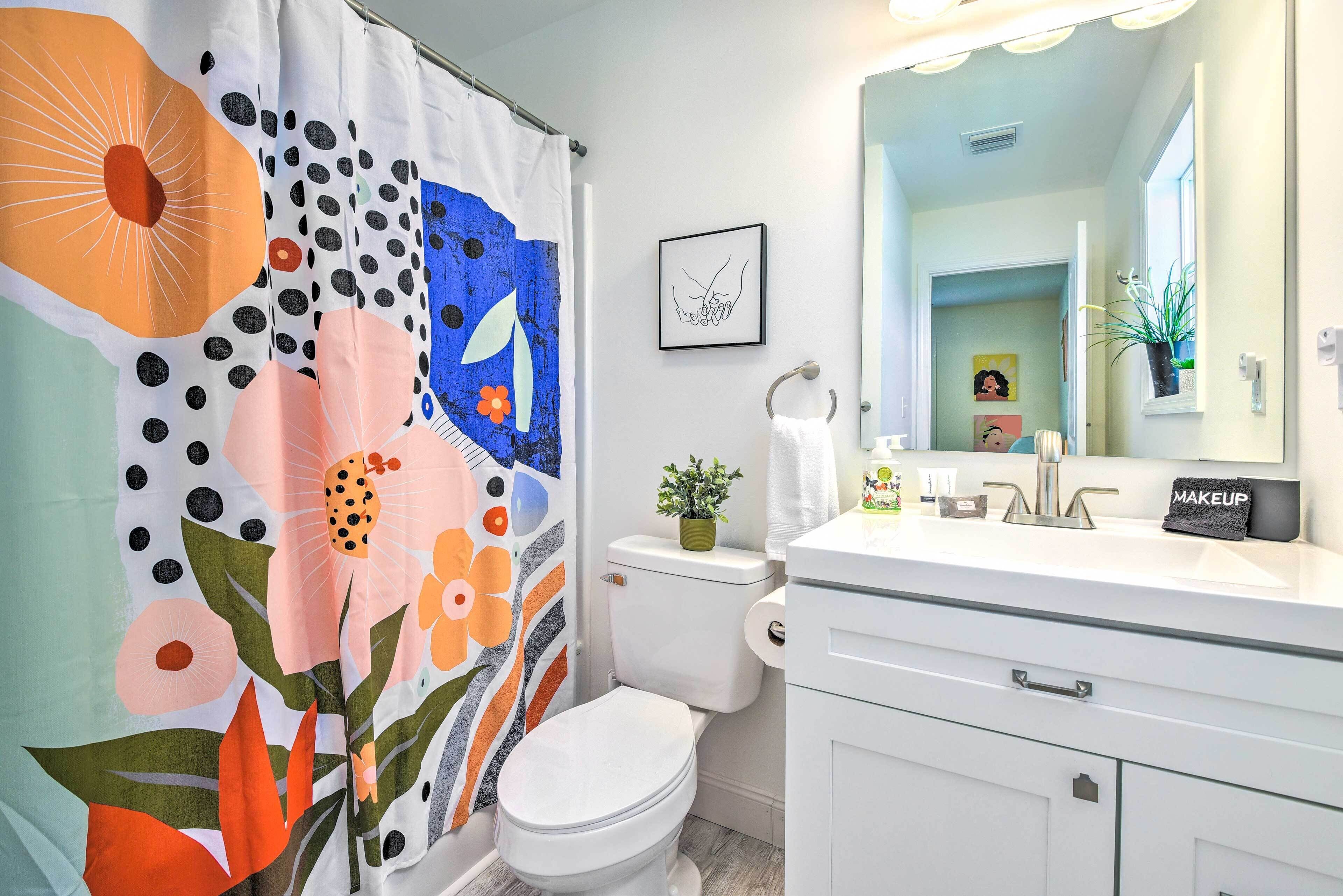 Une salle de bain équipée de toilettes, d’un lavabo et d’un rideau de douche orné de motifs floraux.