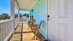 A covered porch with wooden chairs and a table, white railings, and a light blue exterior wall. - Near Downtown + Ocean: Sarasota Getaway (Sarasota)