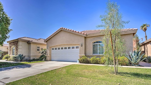 A two-story house with a beige facade, a red-tiled roof, and a white garage door. - 2 Mi to Coachella: Indio Home w/ Fire Pit! (Indio)