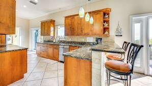 A spacious kitchen with wooden cabinets, granite countertops, and a central island with seating.