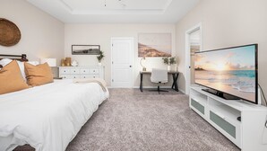 Ein Schlafzimmer mit Bett, Schreibtisch, Fernseher und Deckenventilator.