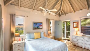 A bedroom with a bed, nightstands, a ceiling fan, a window with curtains, a door leading outside, and a dresser. - St Thomas Cliffside Villa With Pool & Hot Tub! (St. Thomas)