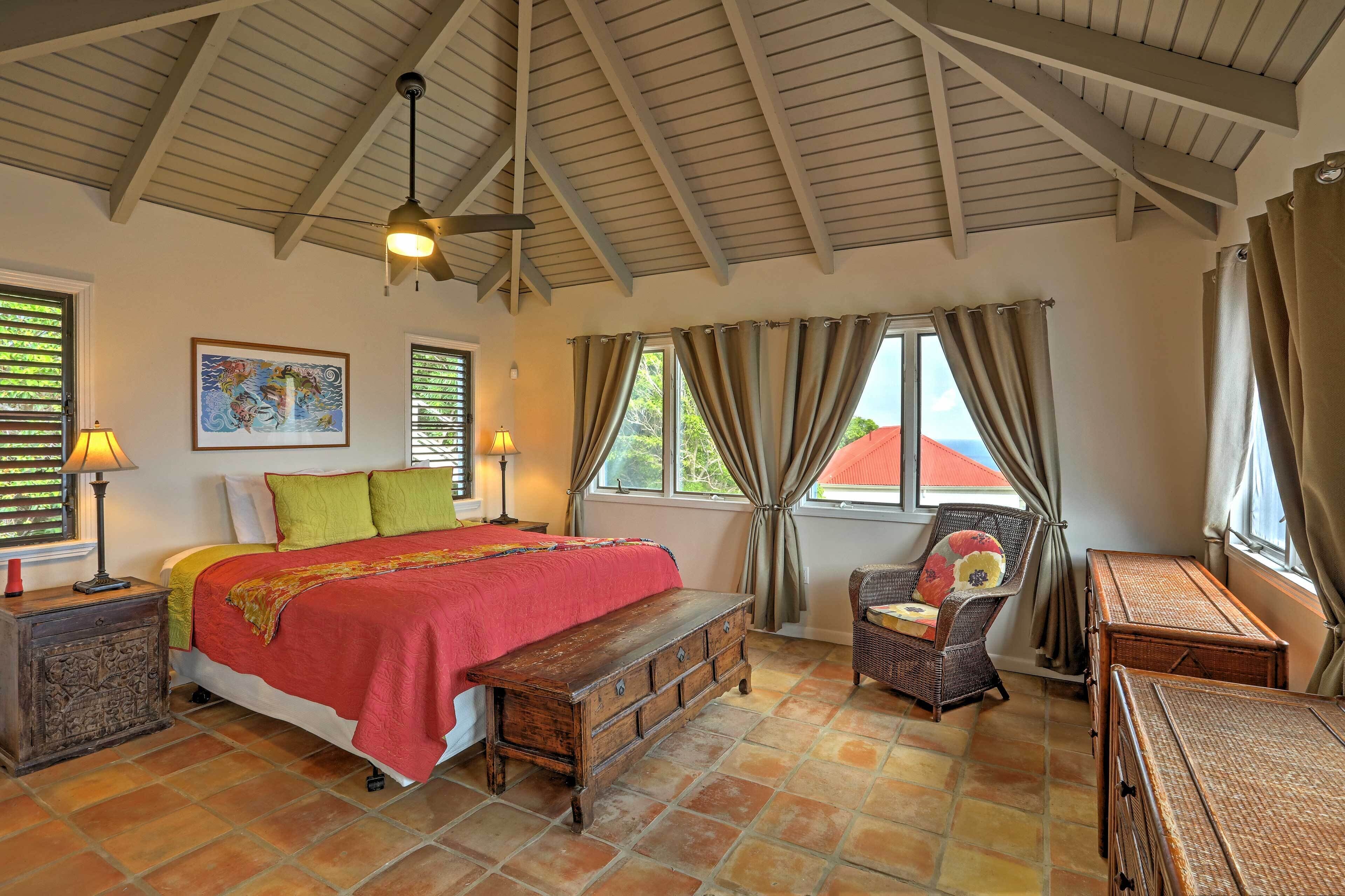 A bedroom with a bed, a wooden bench, a chair, a lamp, and a painting on the wall.