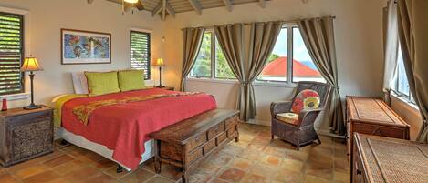 A bedroom with a bed, a wooden bench, a chair, a lamp, and a painting on the wall.