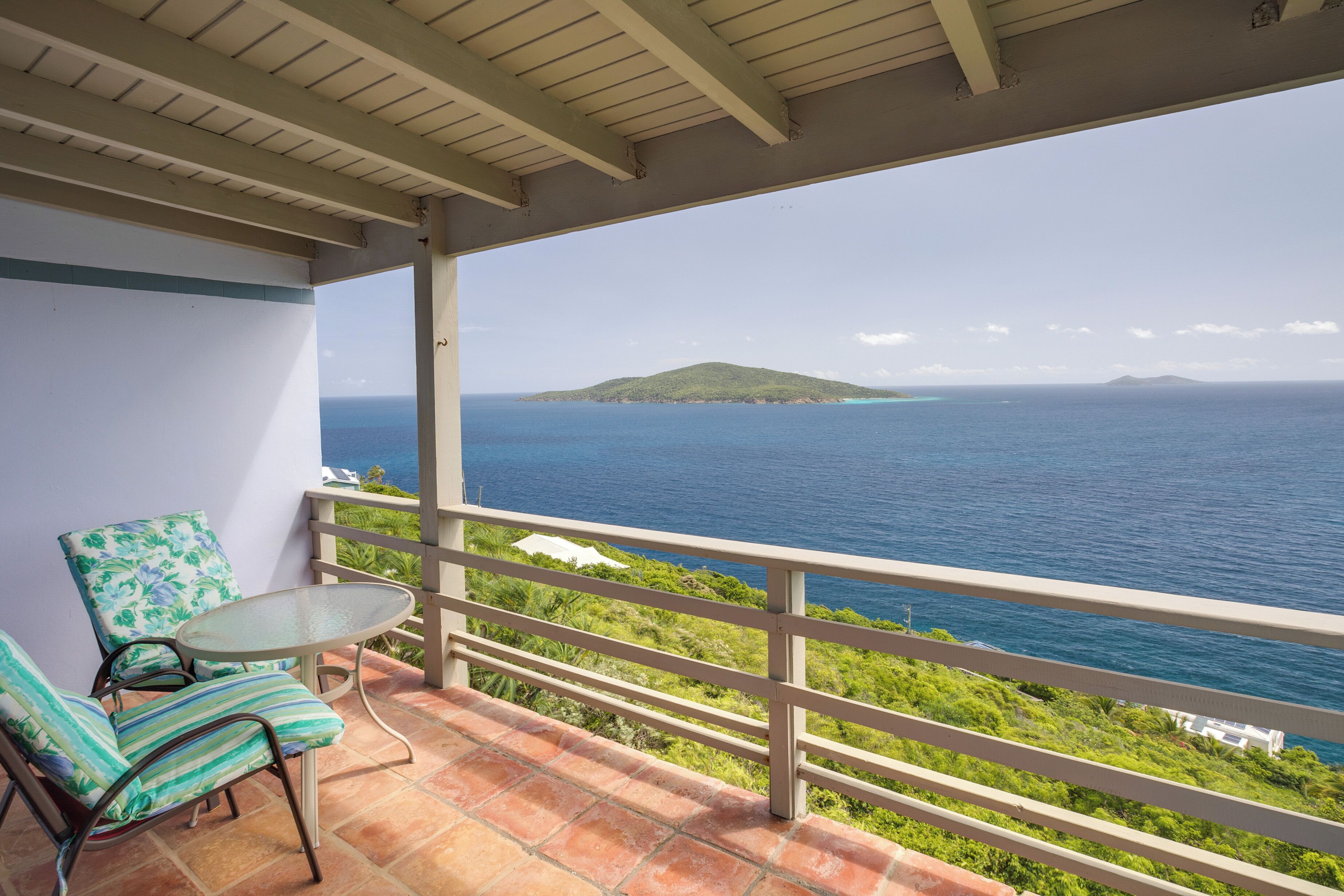 A balcony with a view of the ocean and a distant island.