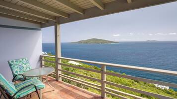 A balcony with a view of the ocean and a distant island.