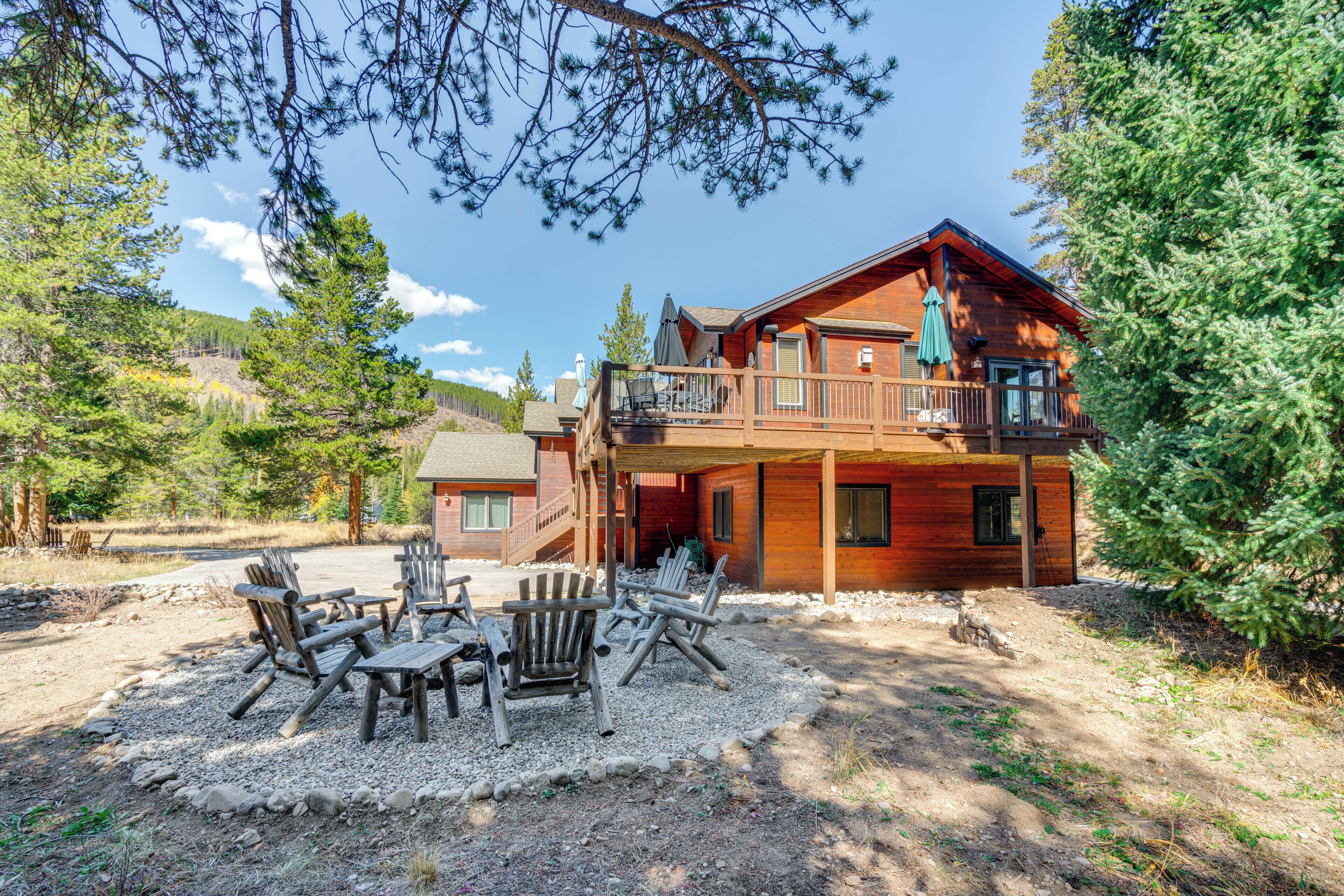 Un chalet doté d’une terrasse, de meubles de jardin et offrant une vue sur la forêt environnante.