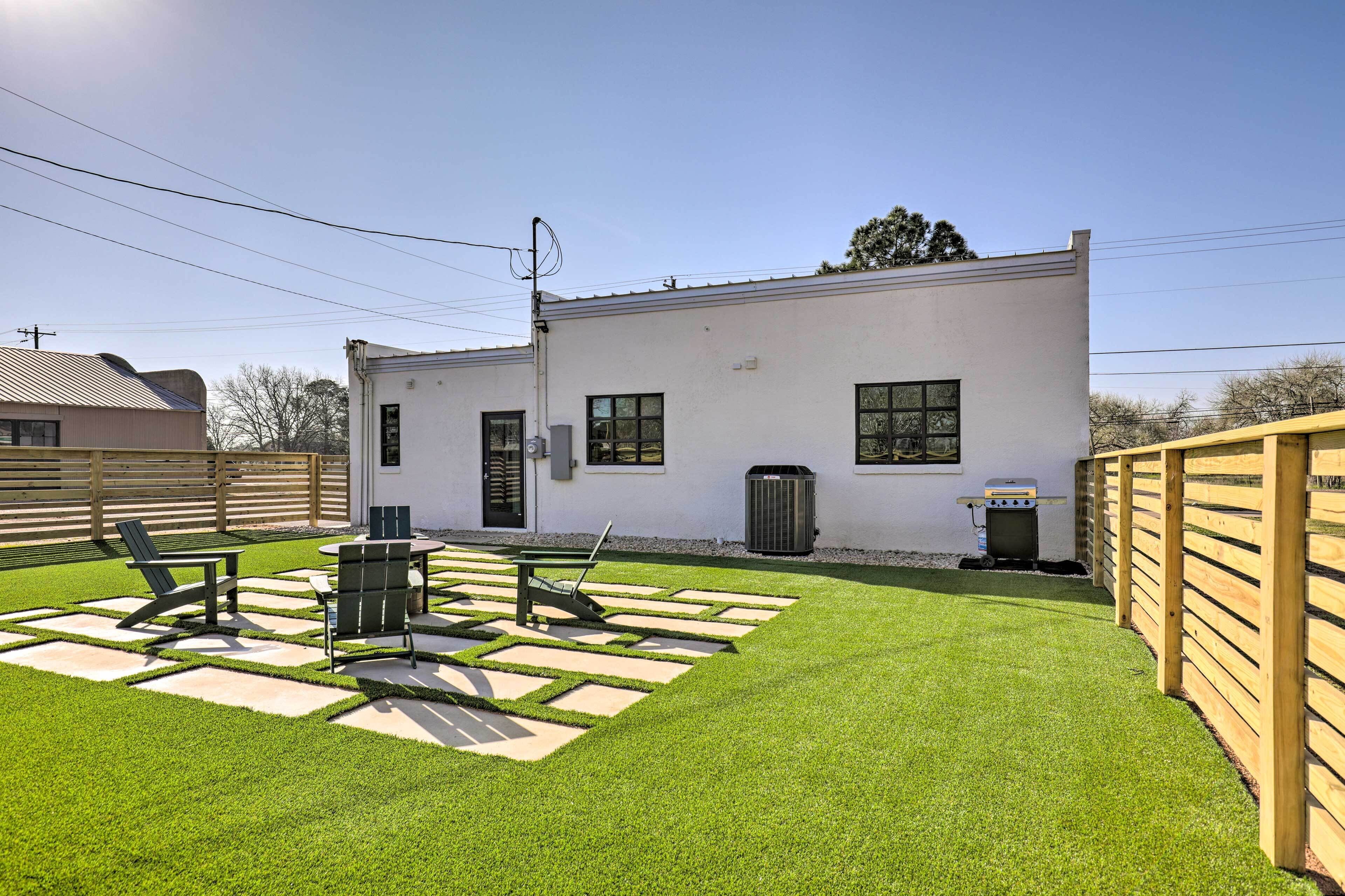 A modern building with a flat roof, a small patio area with a table and chairs, and a well-maintained lawn.