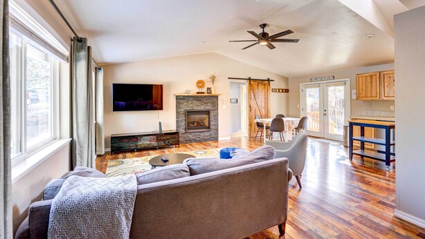 A spacious living room with a fireplace, a ceiling fan, and a large window with curtains. - Pet-friendly Bend Home ~ 2 Mi to Downtown (Bend)