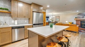A modern kitchen with stainless steel appliances, wooden cabinets, and a central island with stools. - 1 Block to Main St: Modern Breckenridge Condo! (Breckenridge)