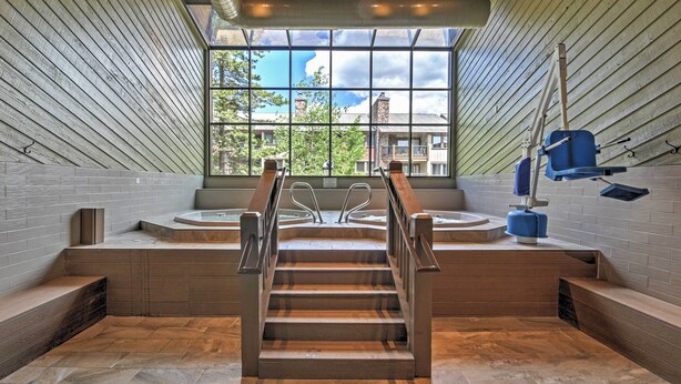 A modern spa area with a large window, wooden steps, and a blue massage table. - 1 Block to Main St: Modern Breckenridge Condo! (Breckenridge)