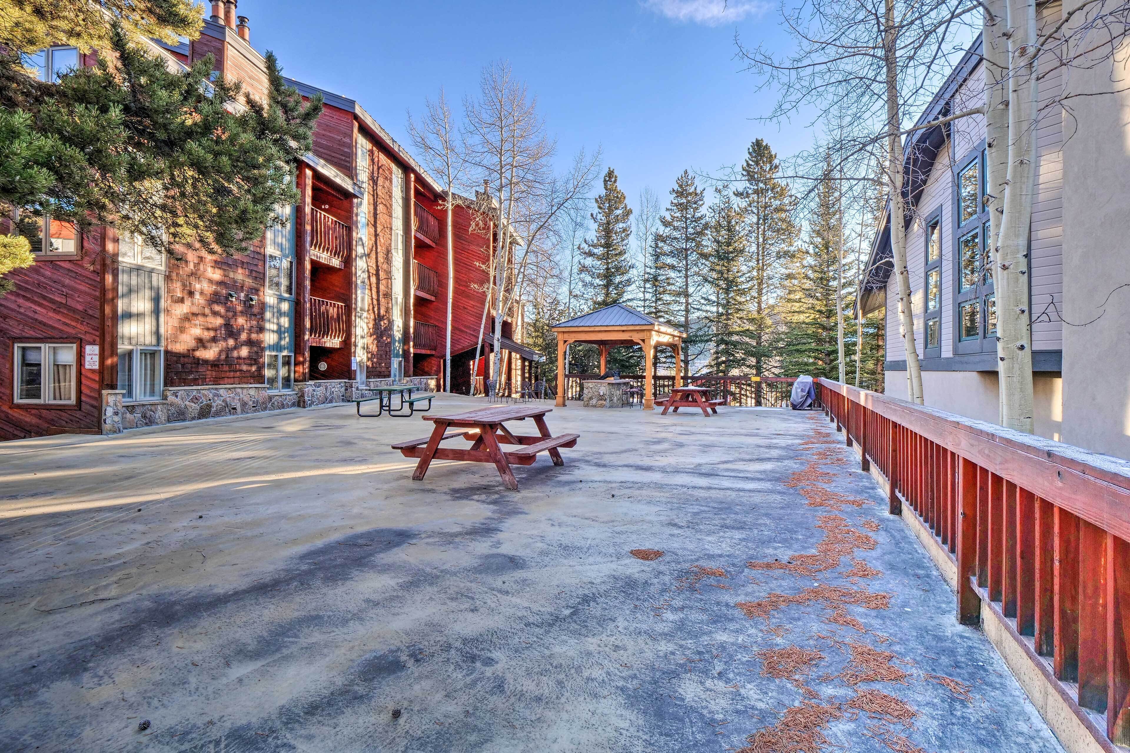 A covered outdoor area with picnic tables, a gazebo, and a red railing.
