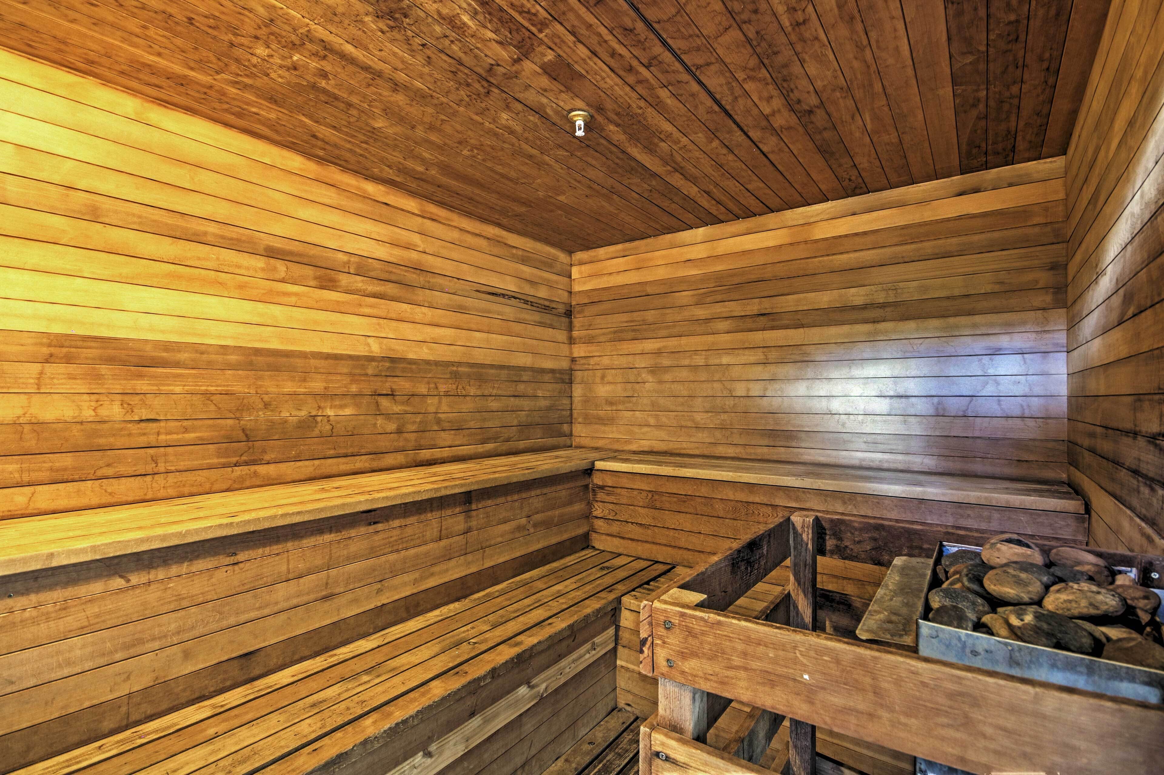 A wooden sauna with benches and a wood-burning stove.
