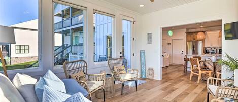 A spacious living area with a large window, wicker furniture, and a view of a multi-story building.