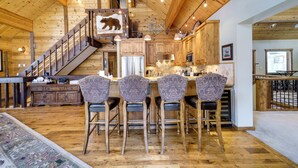 A spacious kitchen with wooden cabinets, a central island with bar stools, and a staircase leading to a loft area. - 'one Moose Lodge' Tahoe Donner Vacation Rental! (Truckee)