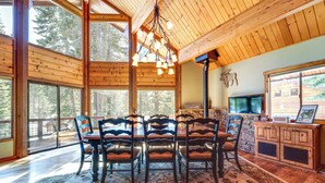 A wooden dining area with a large table and chairs, a rug, and a stone fireplace. - 'one Moose Lodge' Tahoe Donner Vacation Rental! (Truckee)