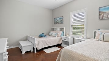 A bedroom with a bed, a nightstand, a dresser, and a window with blinds.