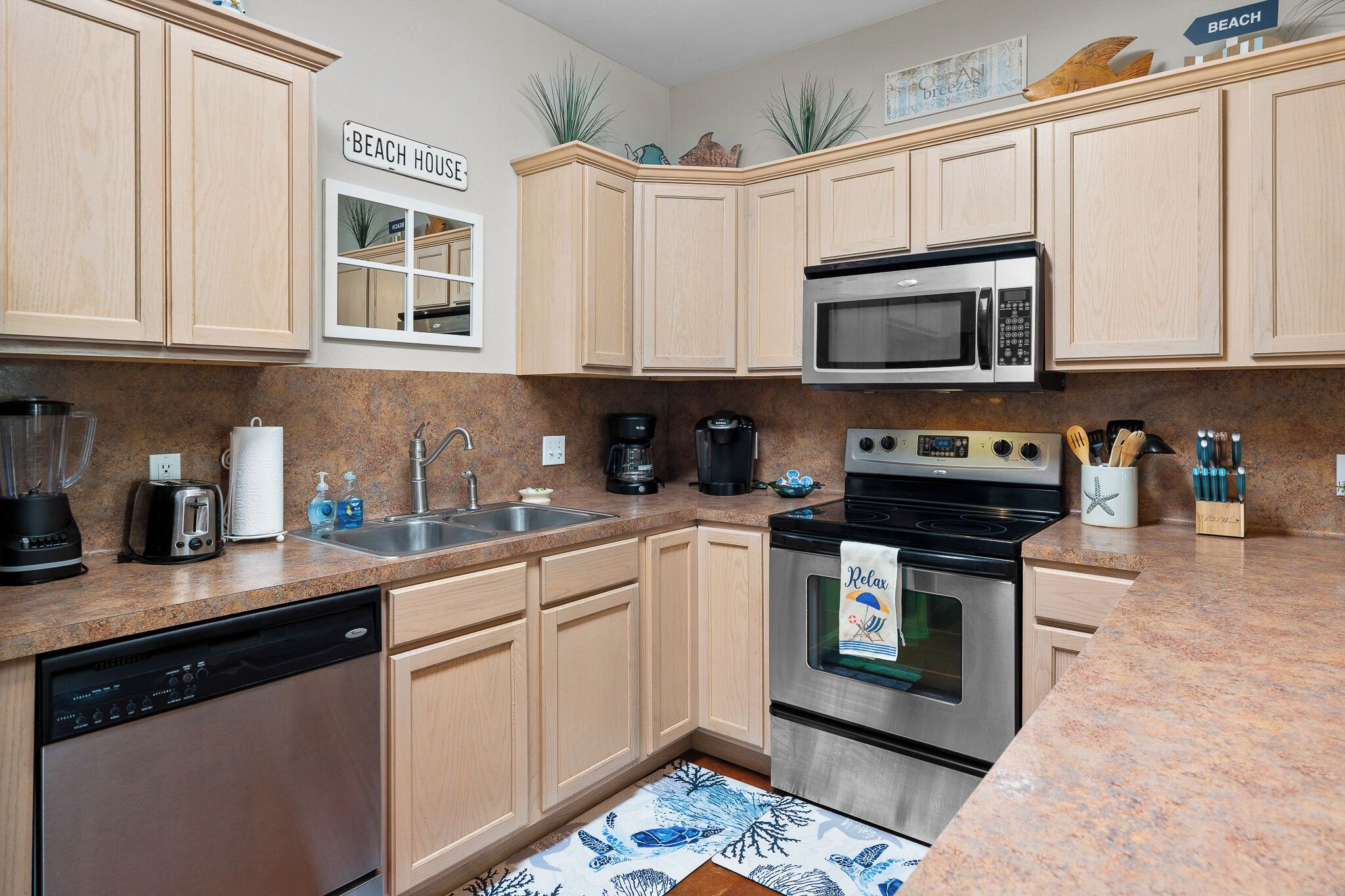 A kitchen with wooden cabinets, a stainless steel dishwasher, a microwave, a coffee maker, and a stove.