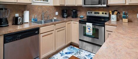 A kitchen with wooden cabinets, a stainless steel dishwasher, a microwave, a coffee maker, and a stove.