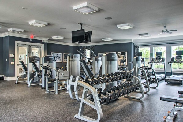 A gym with various exercise equipment, a television, and large windows.