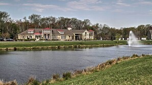 A large building with a pond in front, a fountain, and trees in the background. - 5 Mi to Bethany Beach: Townhome w/ Community Perks (Millville)