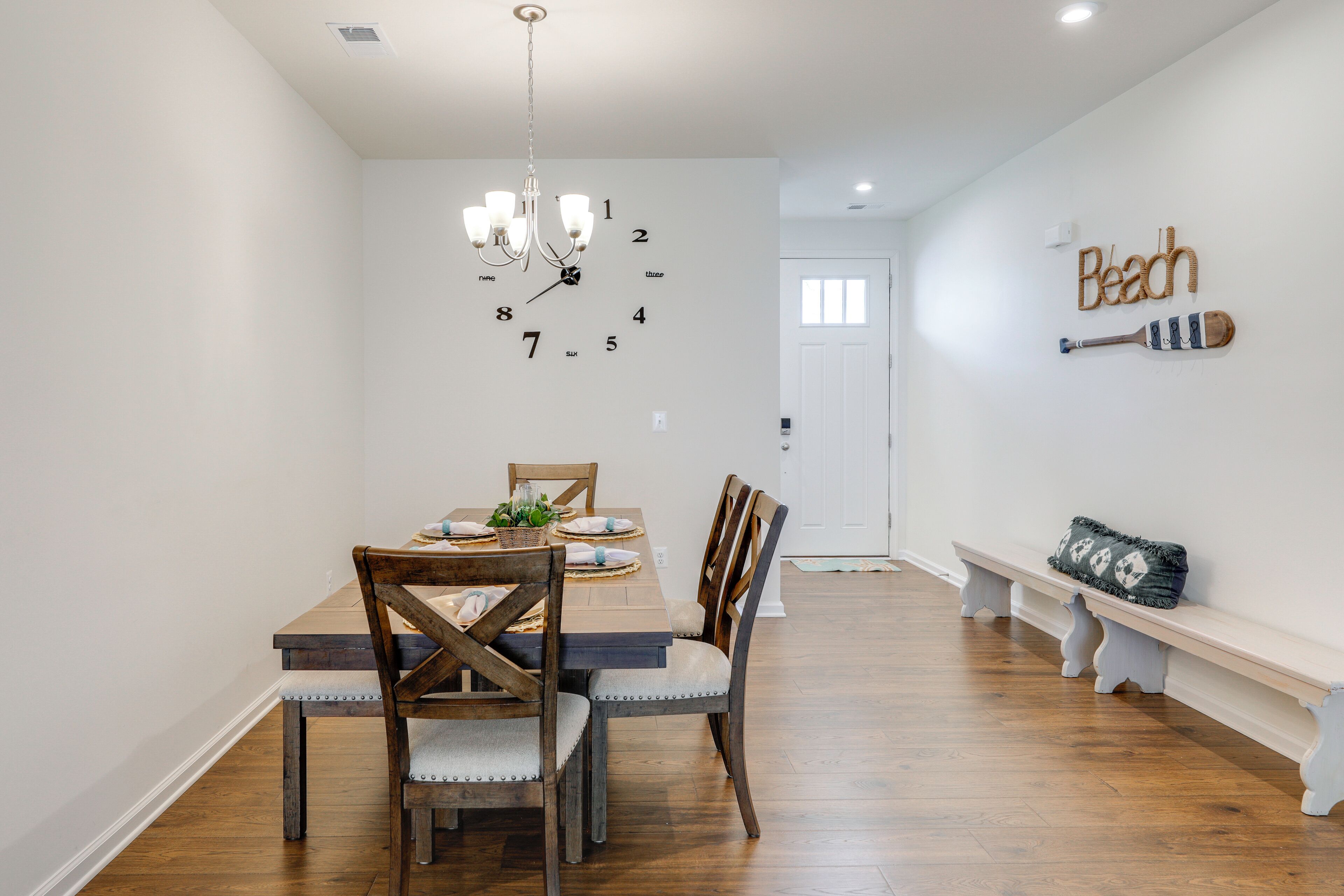 A dining area with a wooden table, chairs, and a wall clock.