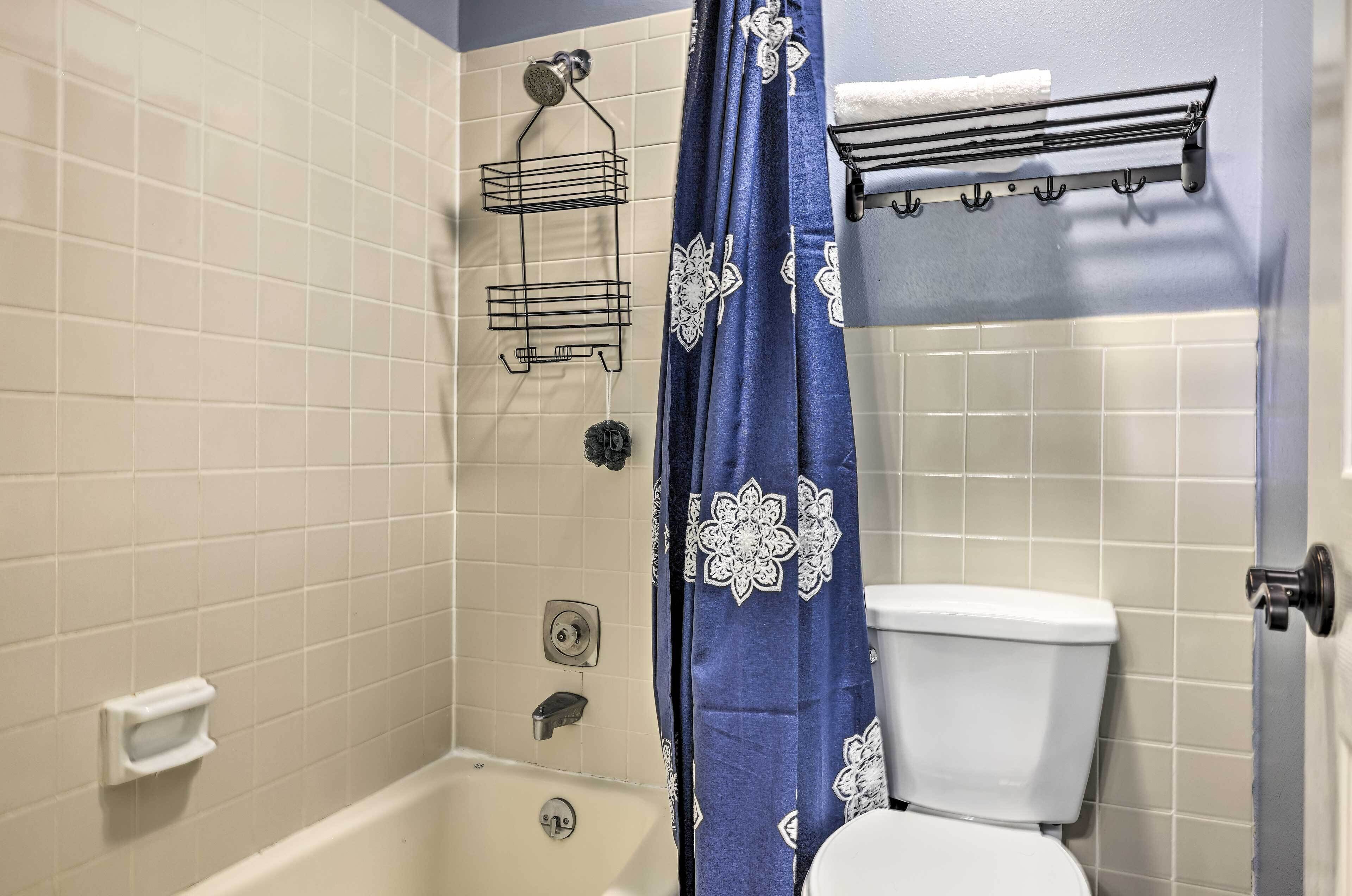 Een badkamer met een bad, toilet en douchegordijn.
