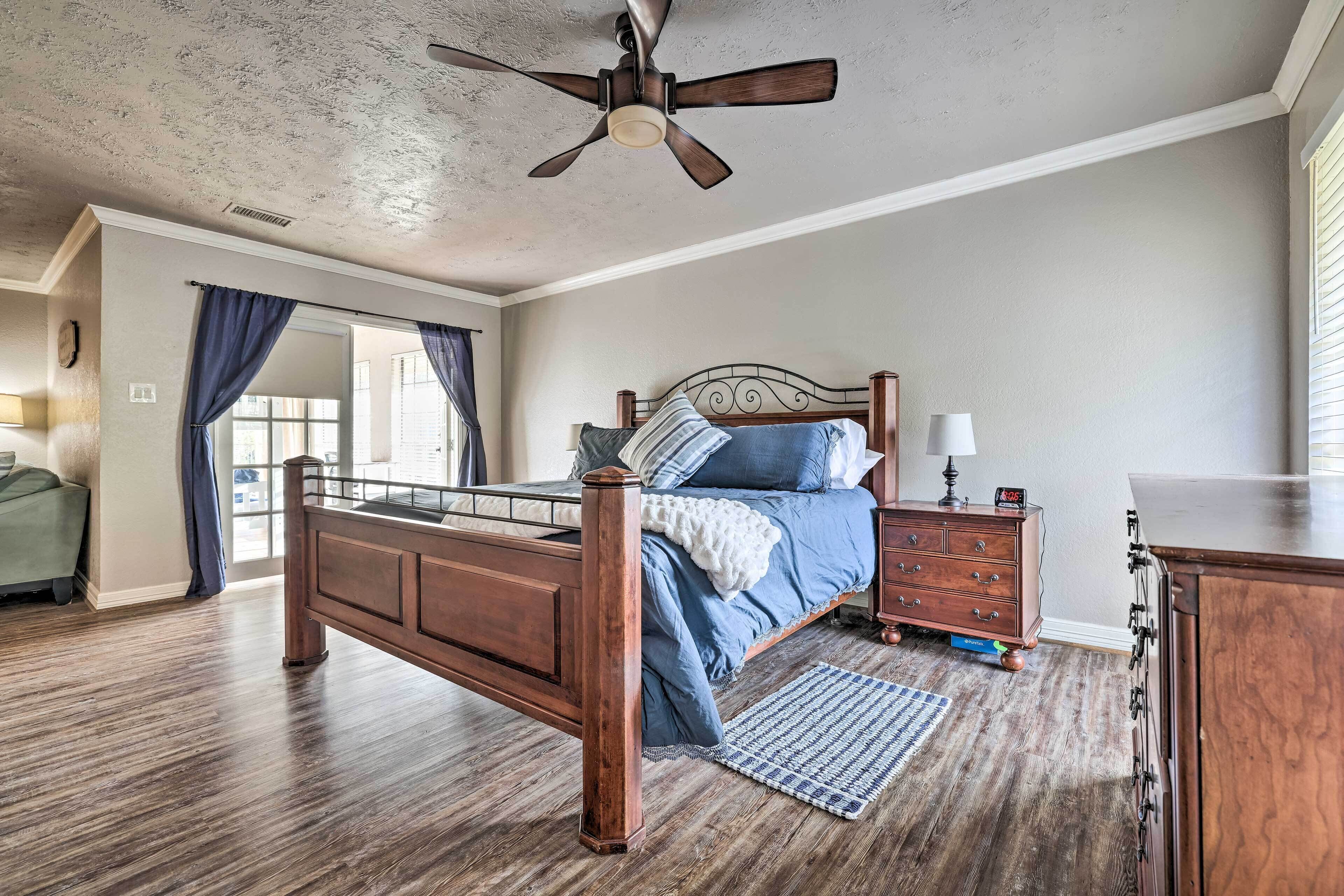 A bedroom with a wooden bed, a nightstand, a dresser, and a ceiling fan.