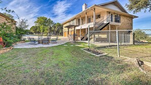 A two-story house with a covered patio, outdoor seating, and a fenced yard. - Canyon Lake Home: Hill Country & Water Views! (Canyon Lake)