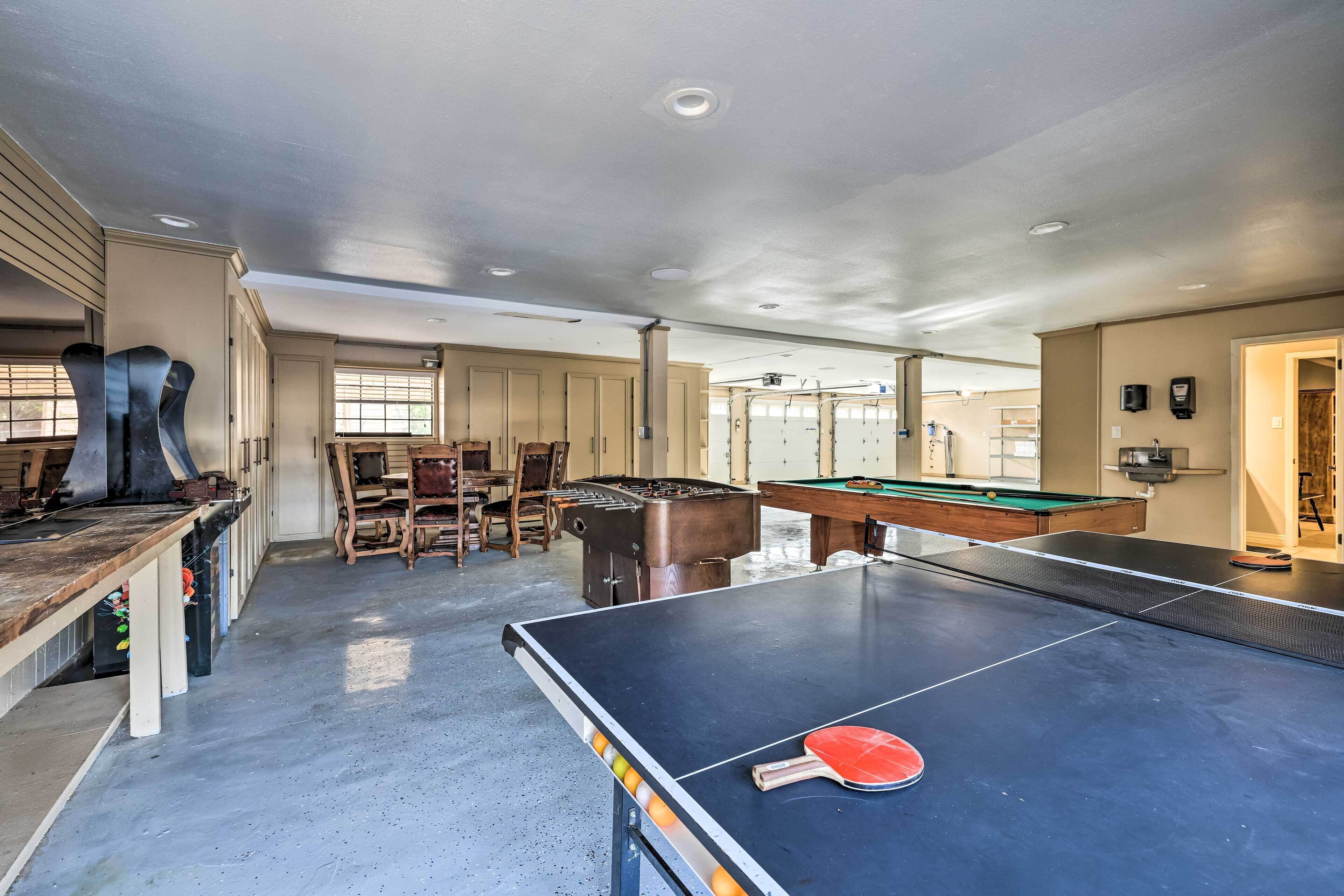 A spacious indoor area with a ping pong table, pool table, and a barbecue grill.