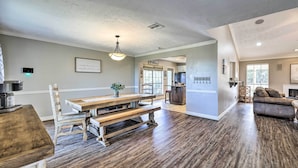A spacious living area with a wooden dining table, a sofa, and a kitchen in the background. - Canyon Lake Home: Hill Country & Water Views! (Canyon Lake)