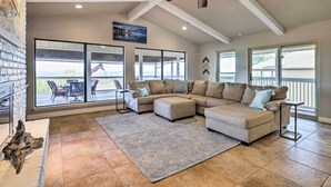 A spacious living room with a sectional sofa, large windows, and a ceiling fan. - Canyon Lake Home: Hill Country & Water Views! (Canyon Lake)