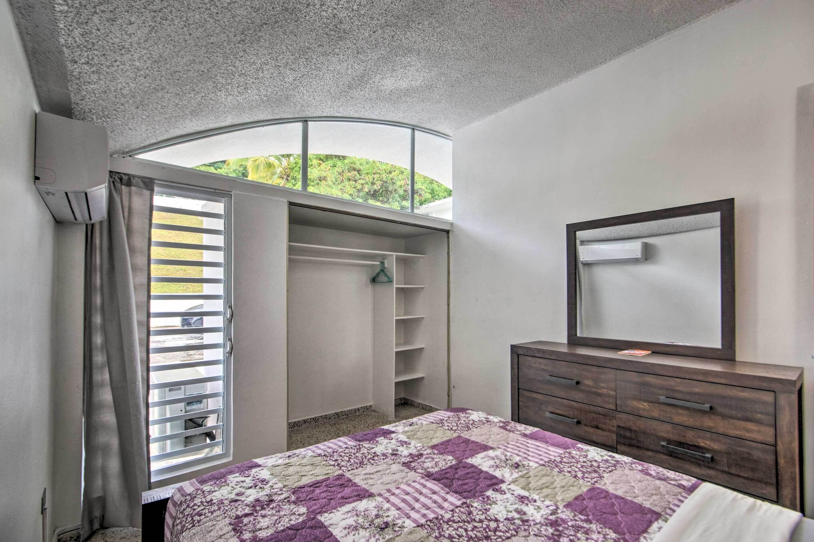 Une chambre à coucher comprenant un lit, une commode, un miroir et un placard avec des étagères.