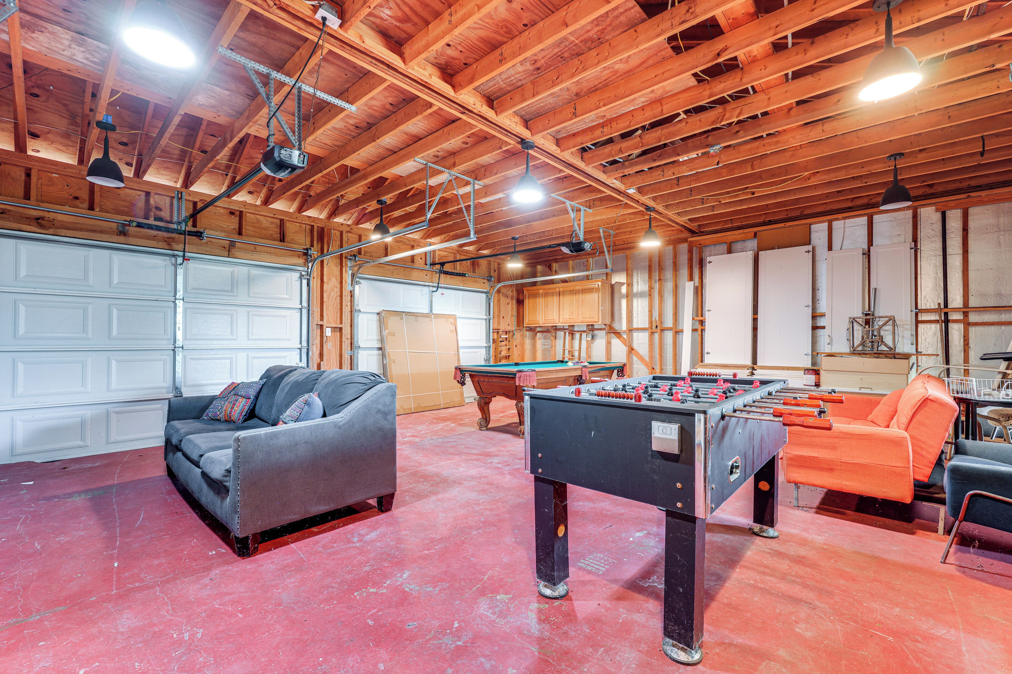 A spacious indoor area with a foosball table, a pool table, and a sofa.