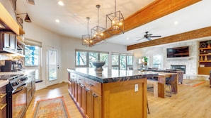A spacious kitchen with a large island, wooden cabinetry, and a stone countertop. - Modern Fischer House w/ Deck, Fire Pit & Hot Tub! (Canyon Lake)