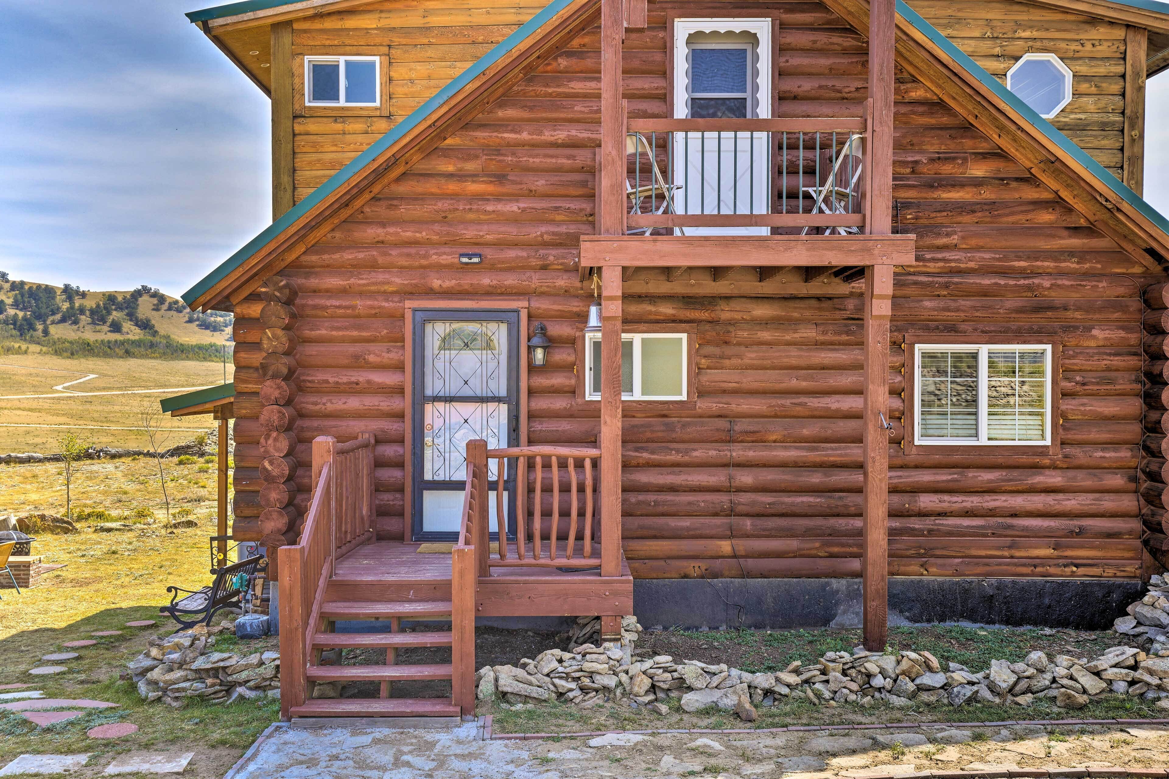 A log cabin with a balcony, a front door, and a small porch area.