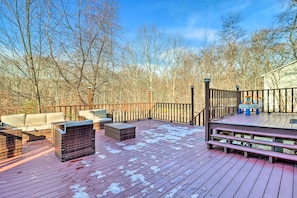 A wooden deck with outdoor furniture, a barbecue grill, and a view of a forested area.