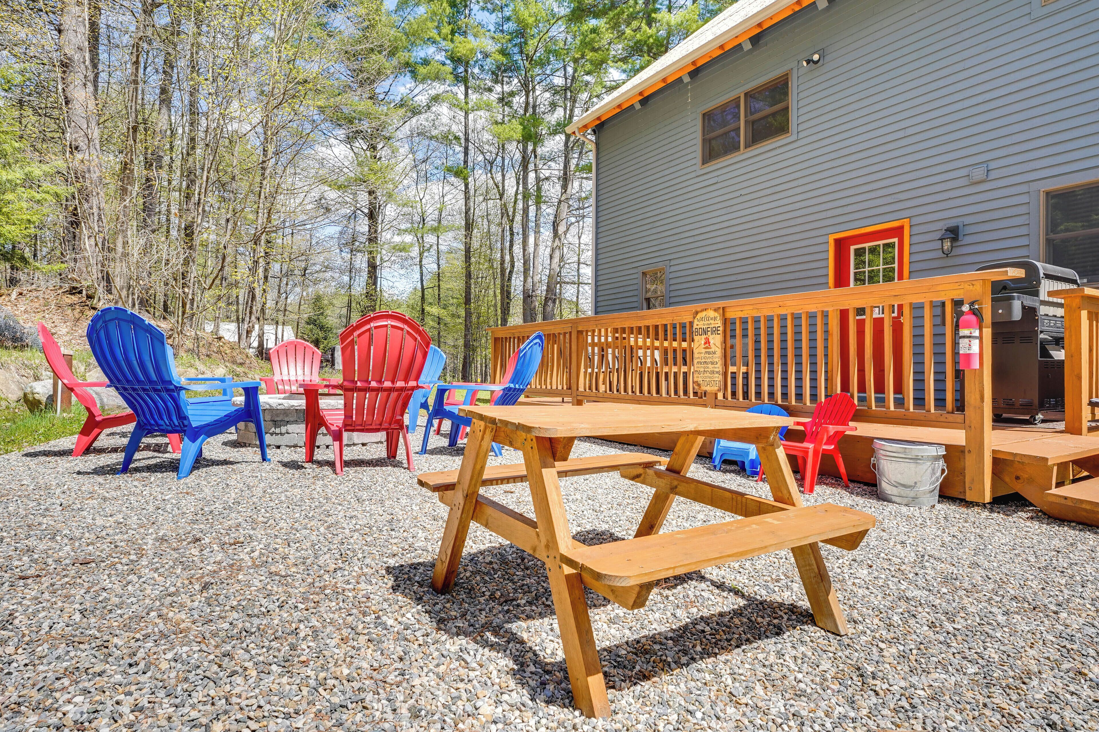 Un espacio al aire libre con mesas de picnic de madera y sillas Adirondack de colores.