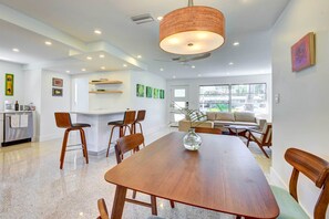 A modern kitchen with white cabinets, a built-in oven, and a dining area with a wooden table and chairs. - Charming Sarasota Vacation Home Near Downtown (Sarasota)