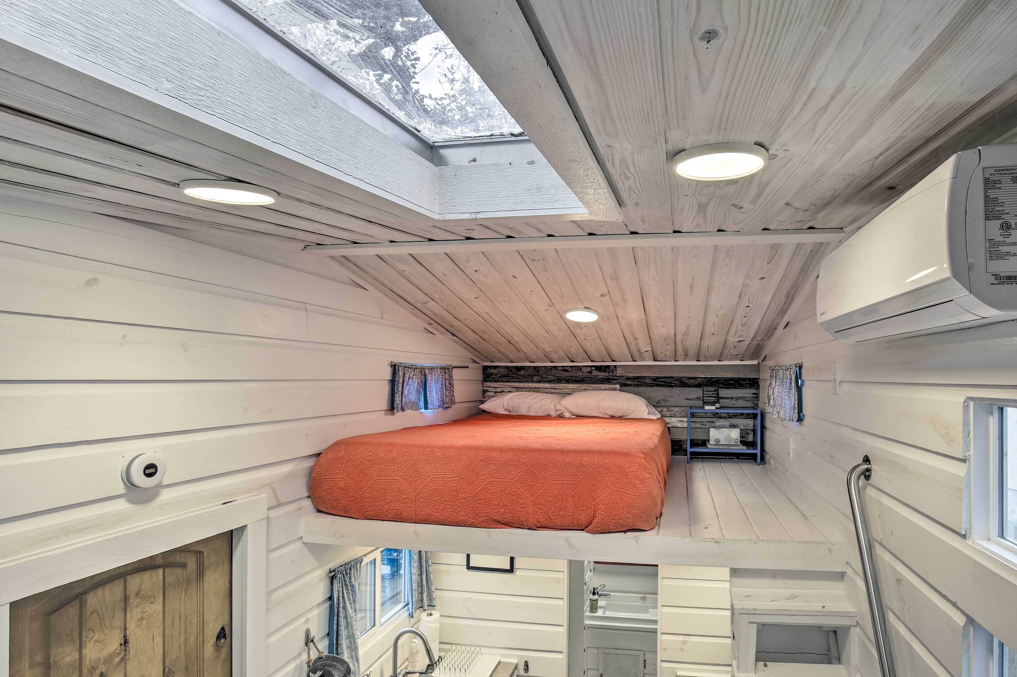 Une cabine compacte et bien éclairée, dotée d’un lit en mezzanine, d’une lucarne et d’une petite kitchenette.