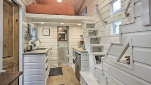 A compact kitchen with white cabinetry, a built-in oven, and a refrigerator. - Unique Stay: 'tiny Everest' San Antonio Home! (San Antonio)