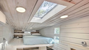 A compact, well-lit room with a bunk bed, skylight, and a small seating area. - Unique Stay: 'tiny Everest' San Antonio Home! (San Antonio)