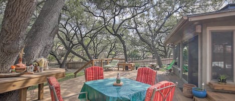 An outdoor deck with a table and chairs, surrounded by trees.
