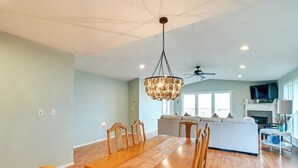 Un comedor amplio con una mesa y sillas de madera, una araña y un ventilador de techo.