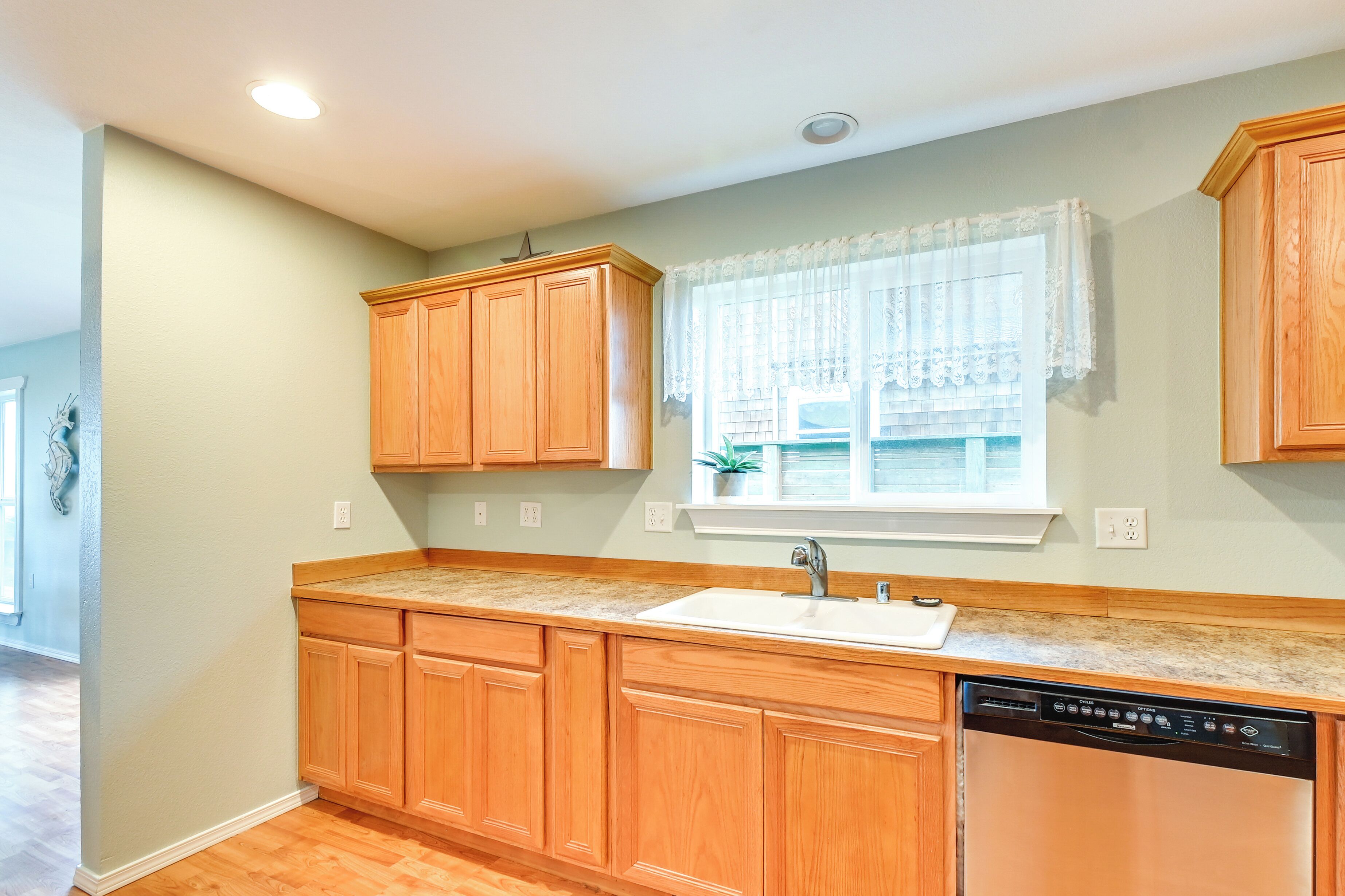 A kitchen with wooden cabinets, a countertop, a sink, and a dishwasher.