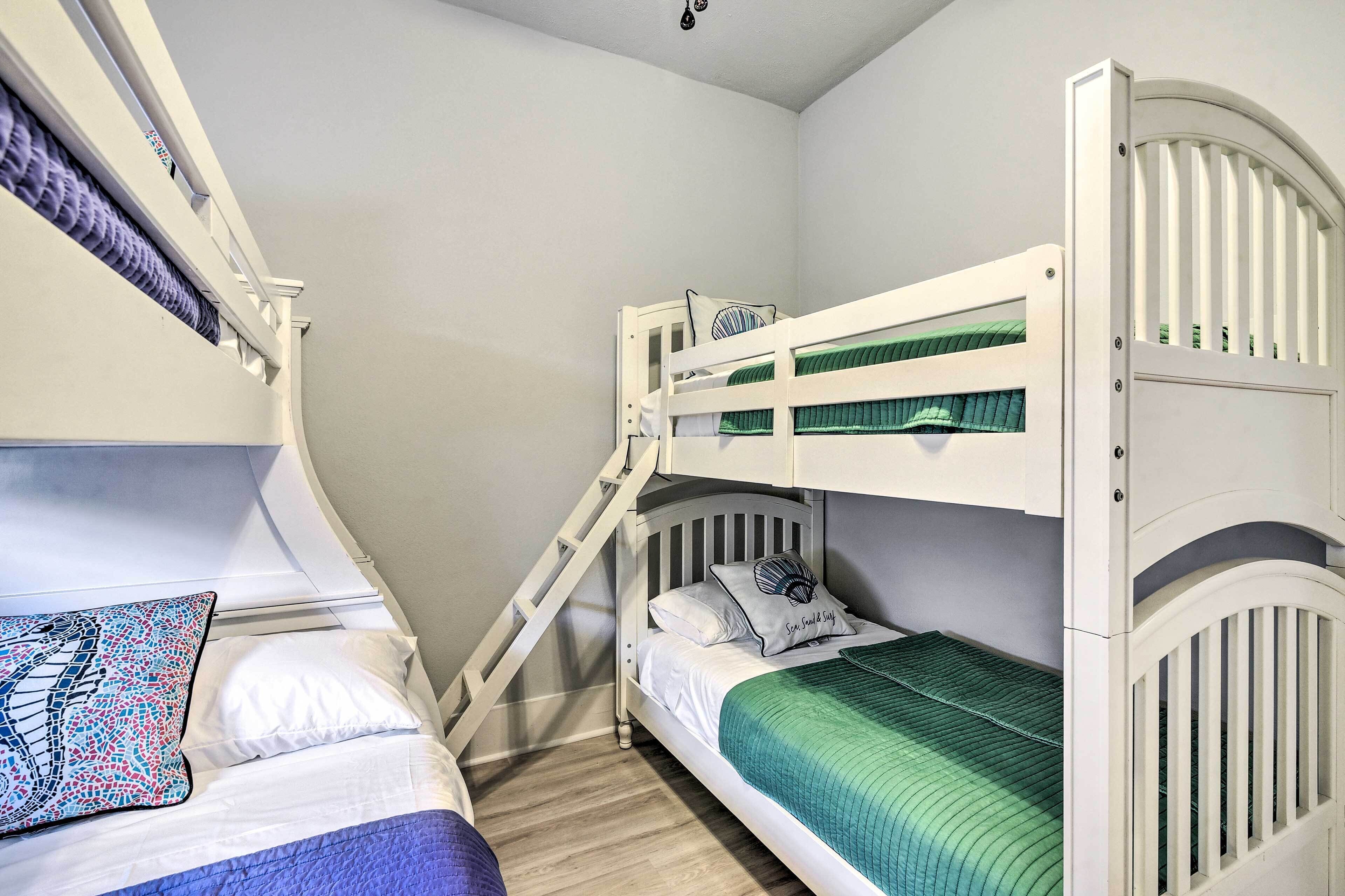 A bunk bed room with a ladder, a bed with a patterned pillow, and a green blanket.