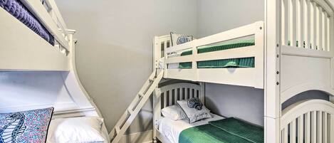 A bunk bed room with a ladder, a bed with a patterned pillow, and a green blanket.